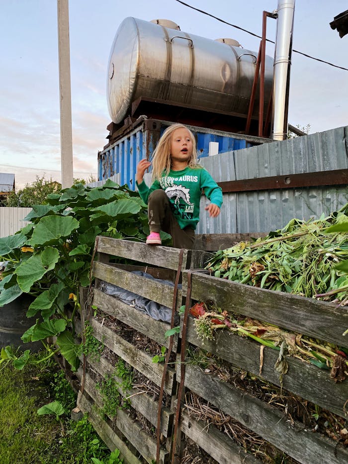 bts-img-02 A girl stands on a compost pile in a Russian garden surrounded by greenery.